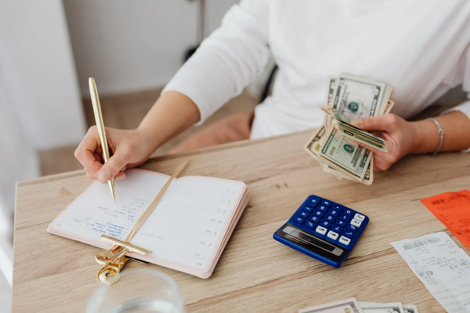US dollar bills, a calculator, and a budget planner on a desk